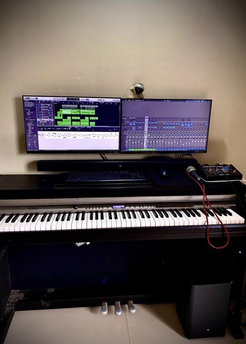 Music production setup with digital piano and two screens