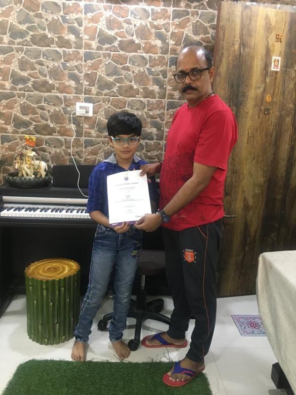 A young student holding a Trinity College London piano certificate