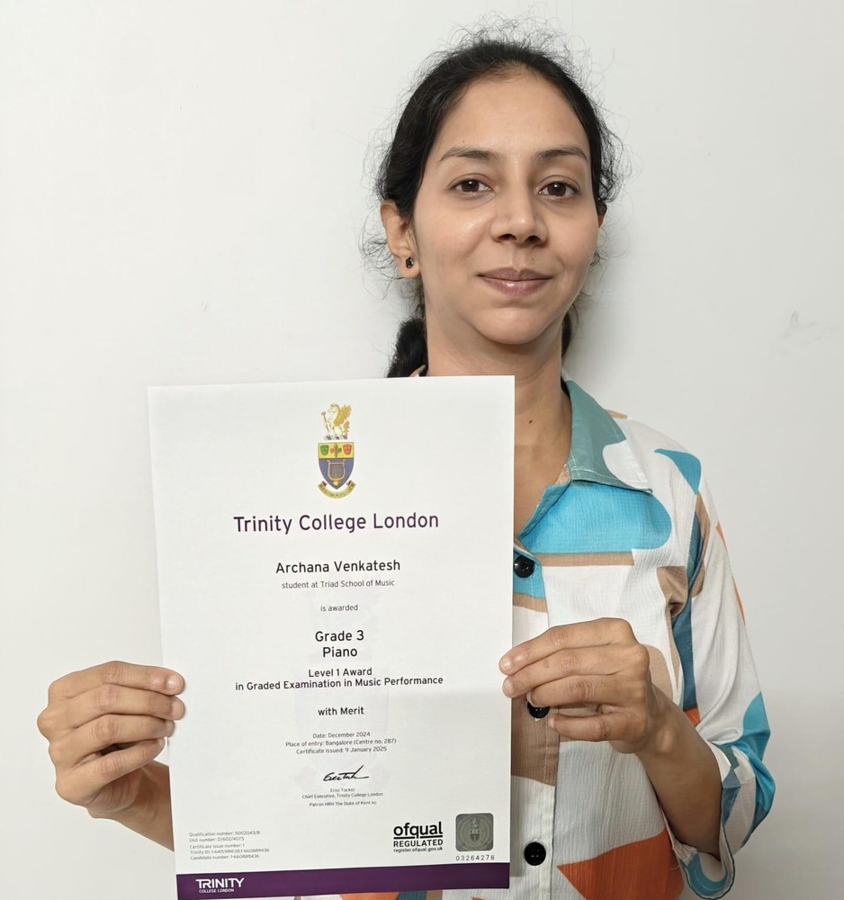 A Triad School of Music student holding her Trinity College London piano certificate